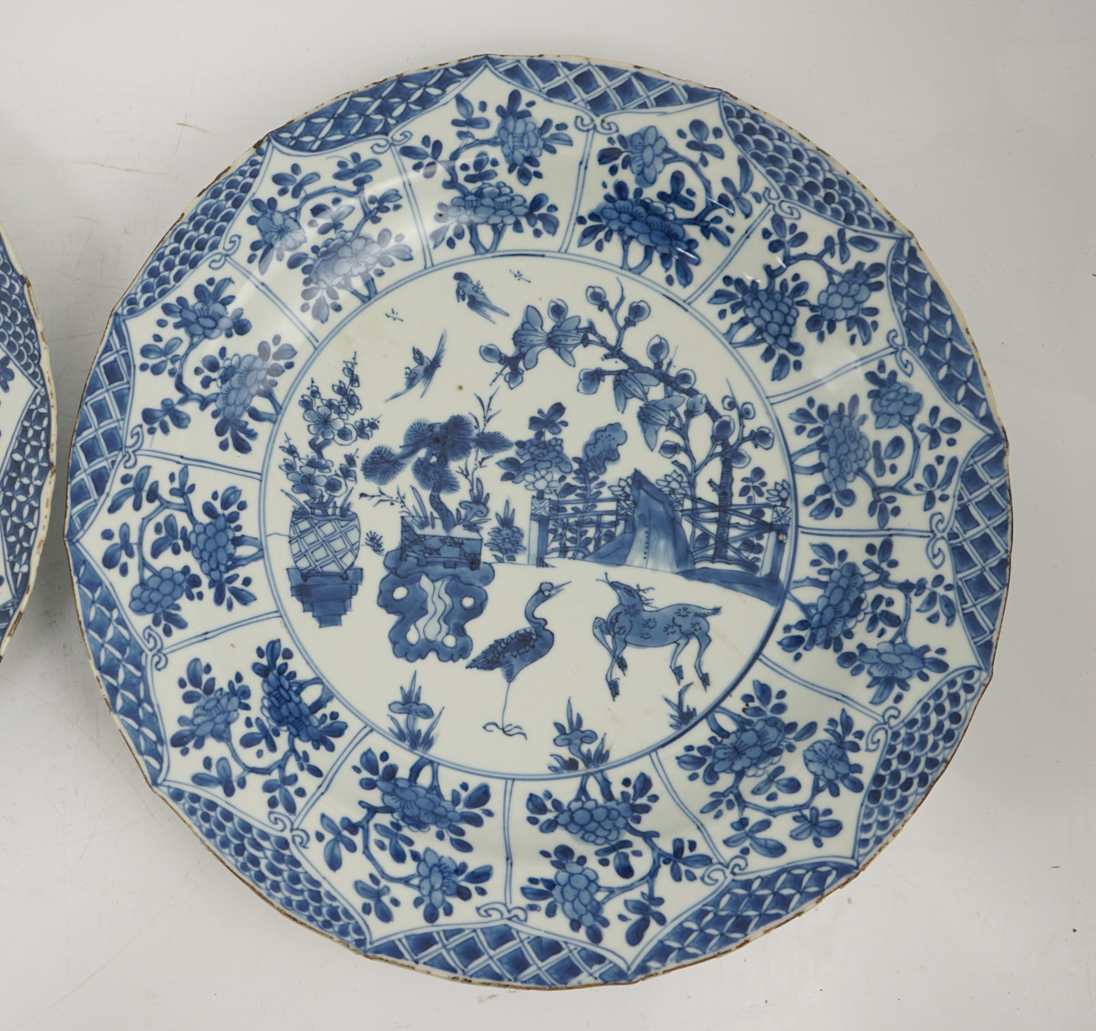A pair of Chinese blue and white ‘garden’ dishes, Kangxi period, fritting and glaze chips